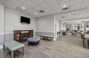 A spacious lobby with a fireplace, seating area, and a television mounted on the wall. - Bluewater 821 (Myrtle Beach)