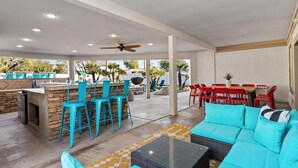 Un'area patio esterna con un bar, posti a sedere e una piscina.