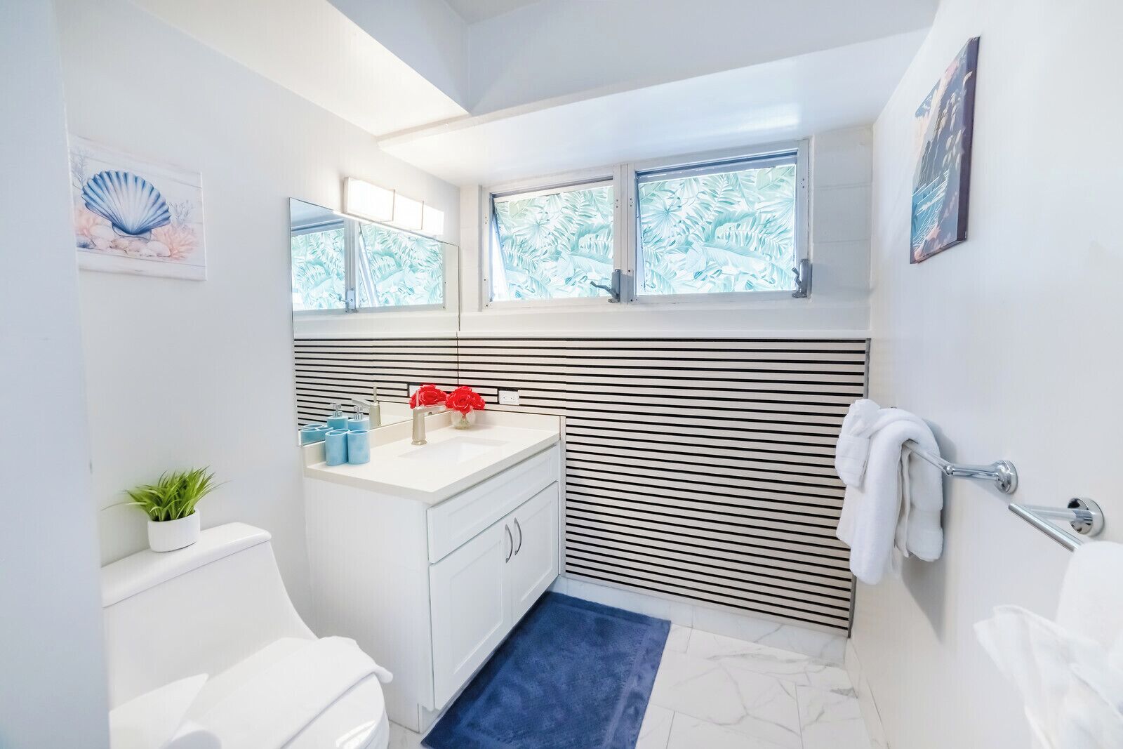 Un baño moderno con tocador blanco, inodoro, lavamanos con espejo y zona de ducha.