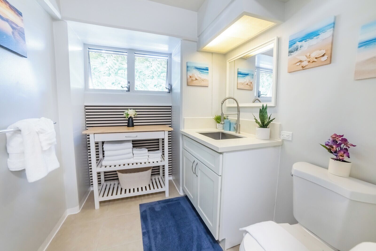 Un baño moderno con lavamanos, espejo y toallero.