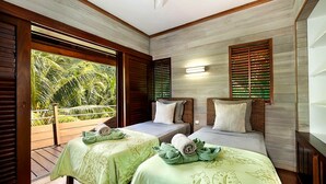 Ein Zimmer mit zwei Betten, Holzboden und Blick auf Grünfläche.