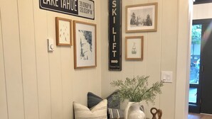 A dining area with a round table, bench seating, framed artwork, and a wall-mounted sign indicating 'LAKE TAHOE'. - Lovely updated  3-bedroom condo on the Lake (Incline Village)