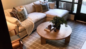A cozy living room with a sectional sofa, a round coffee table, and a large window. - Lovely updated  3-bedroom condo on the Lake (Incline Village)