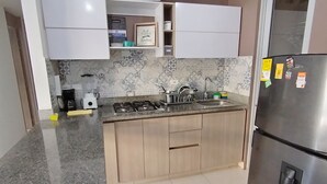 Una cucina moderna con piani di lavoro in granito, un frigorifero in acciaio inox e un piano cottura a gas.