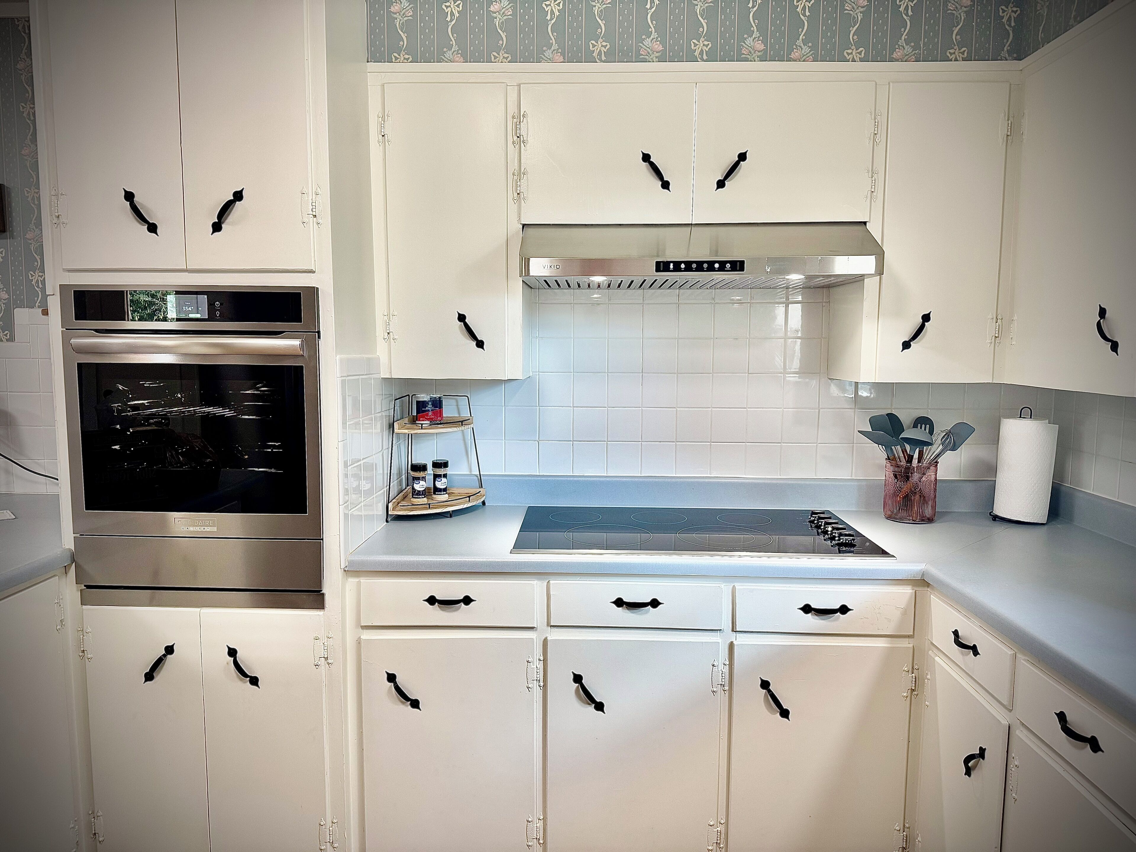 A kitchen with white cabinets, a stainless steel oven, and a modern stove.