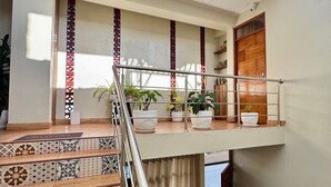 Un intérieur moderne avec un plafond en verre, un escalier aux carreaux décoratifs et des plantes en pot à l’étage supérieur.