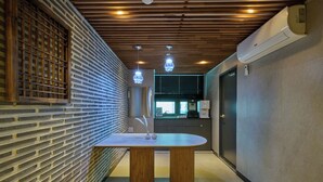 A modern interior with a brick wall, a wooden ceiling, and a table with a vase. - N Joy Stay (Seoul)