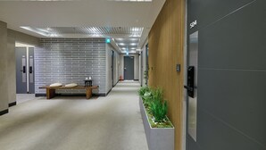 A modern hallway with a bench, a planter with greenery, and a fire extinguisher. - N Joy Stay (Seoul)