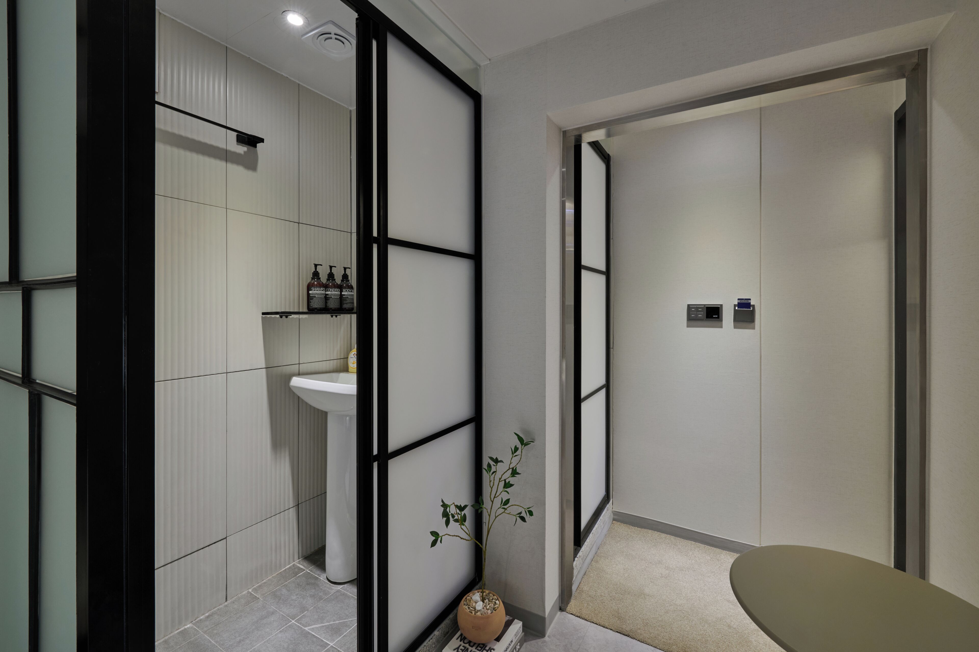 Un baño moderno con un lavamanos, una planta en maceta y un inodoro.