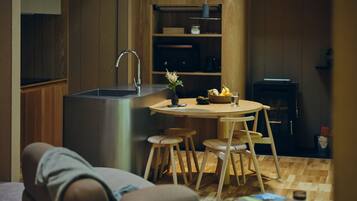 A compact kitchen with a sink, wooden cabinets, and a dining area with stools.