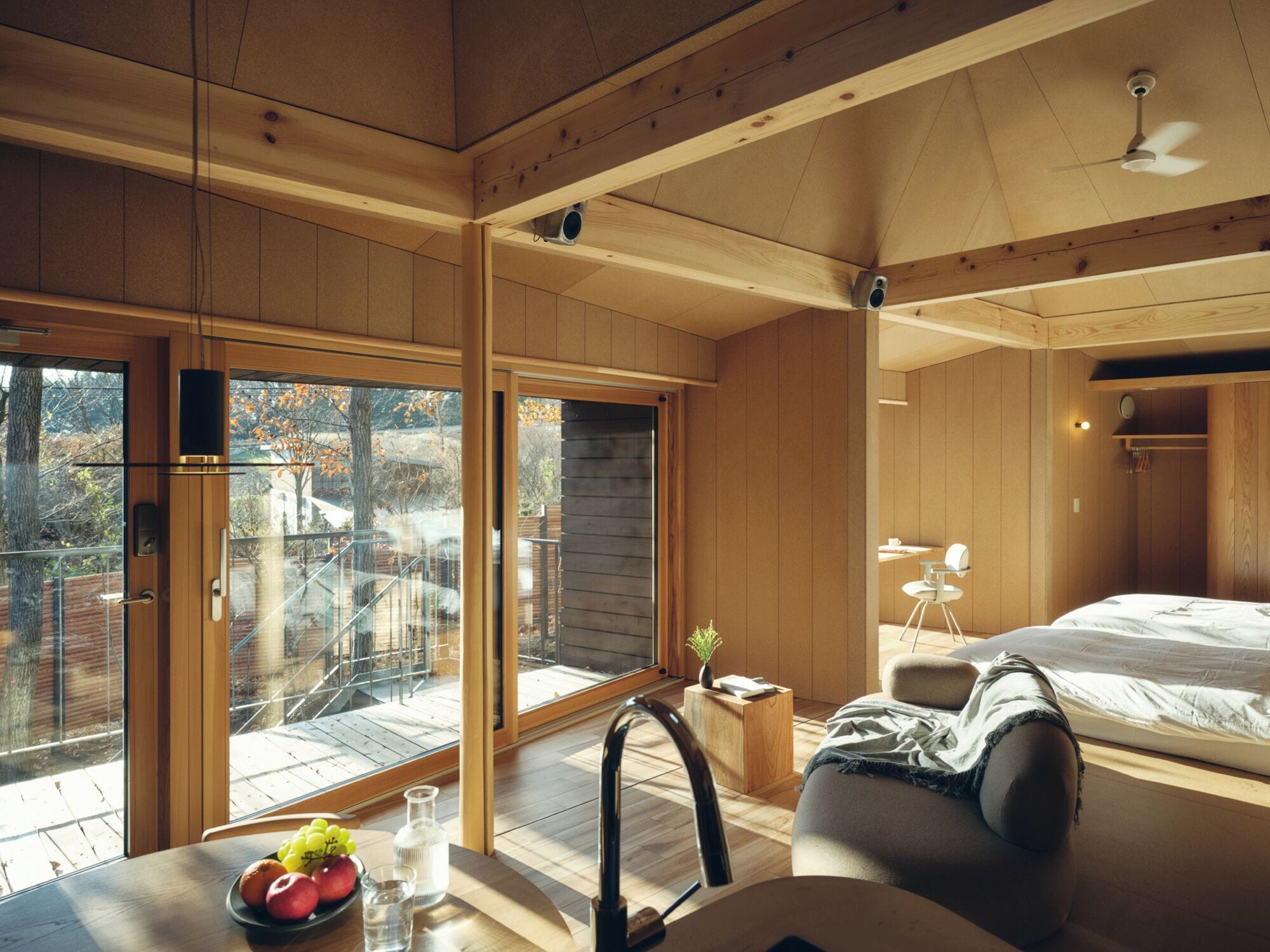 A modern bedroom with a large window, a bed, a desk, and a chair.