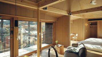 A modern bedroom with a large window, a bed, a desk, and a chair.