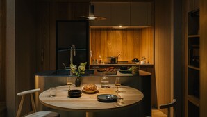 A modern kitchen with wooden cabinets, a central island with a round table, and a hanging light fixture. - SANU 2nd Home Karuizawa 2nd (Miyota)