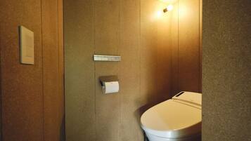 Pieni, moderni kylpyhuone, jossa on wc, paperipyyheannostelija ja valaisin.