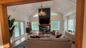 Een ruime woonkamer met een open haard, een grote bank en een kroonluchter.