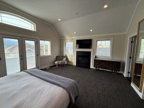 A bedroom with a bed, a fireplace, a TV, and a chair. - Luxury Mountain Retreat in Squamish (Squamish)
