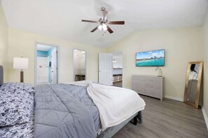 A bedroom with a bed, a ceiling fan, a TV, a dresser, and a mirror.