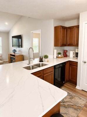 A modern kitchen with a marble countertop, wooden cabinets, a dishwasher, and a built-in oven. - Private 3BR Cottage with Hot Tub (Myrtle Beach)