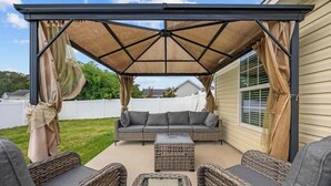 Un patio techado con un conjunto de sofás, dos sillones de mimbre y una mesa de centro.