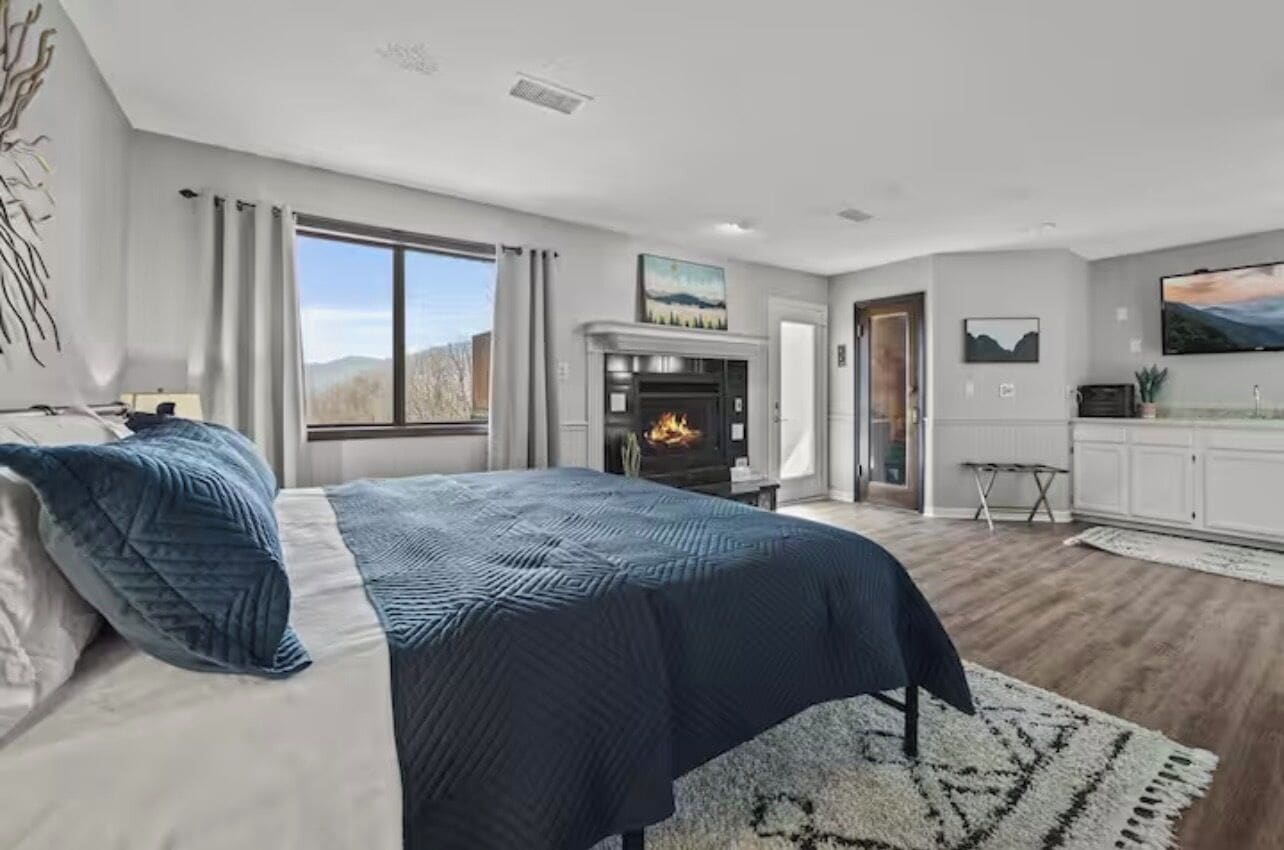 Une chambre moderne avec un grand lit, une cheminée et une vue sur l’extérieur.