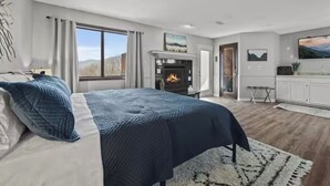 Een moderne slaapkamer met een groot bed, een open haard en uitzicht op de omgeving.
