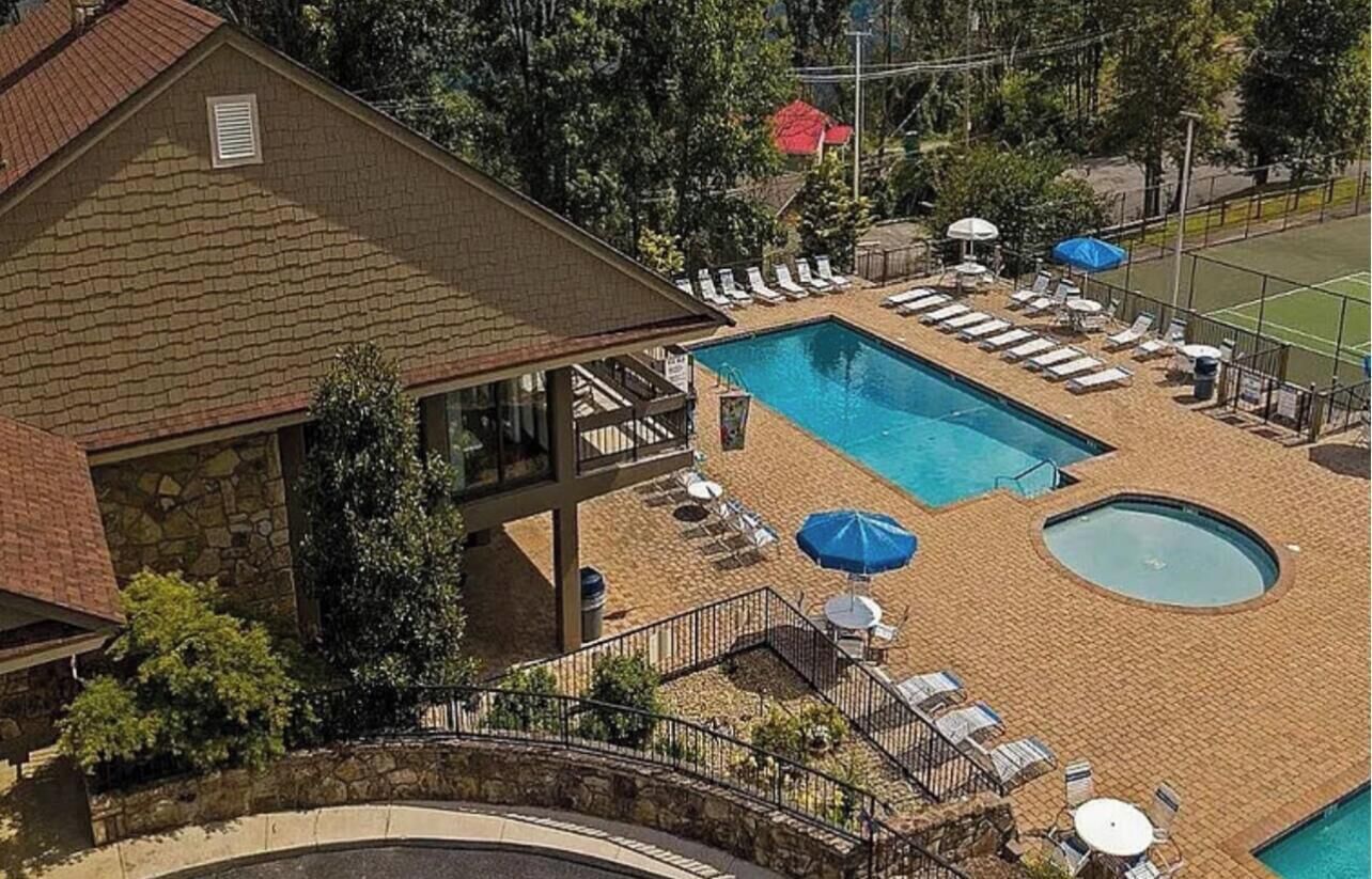 A pool area with lounge chairs and umbrellas, a small circular pool, and a building with a stone facade.