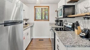 Een kleine keuken met roestvrijstalen apparatuur, granieten werkbladen en een raam voor natuurlijk licht.