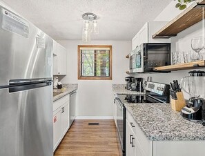 A compact kitchen with stainless steel appliances, granite countertops, and a window providing natural light. - Hot Tub, Sauna, Resort Amenities, Close to downtown (Gatlinburg)
