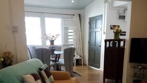 A living room with a sofa, a television, and a dining area in the background.
