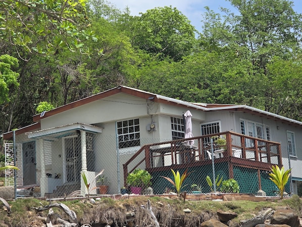 A two-story house with a fenced front yard, a covered porch, and a staircase leading to the upper floor.