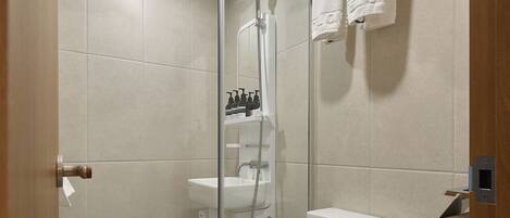 Une salle de bain moderne avec une douche à parois de verre, des toilettes blanches et un porte-serviettes.
