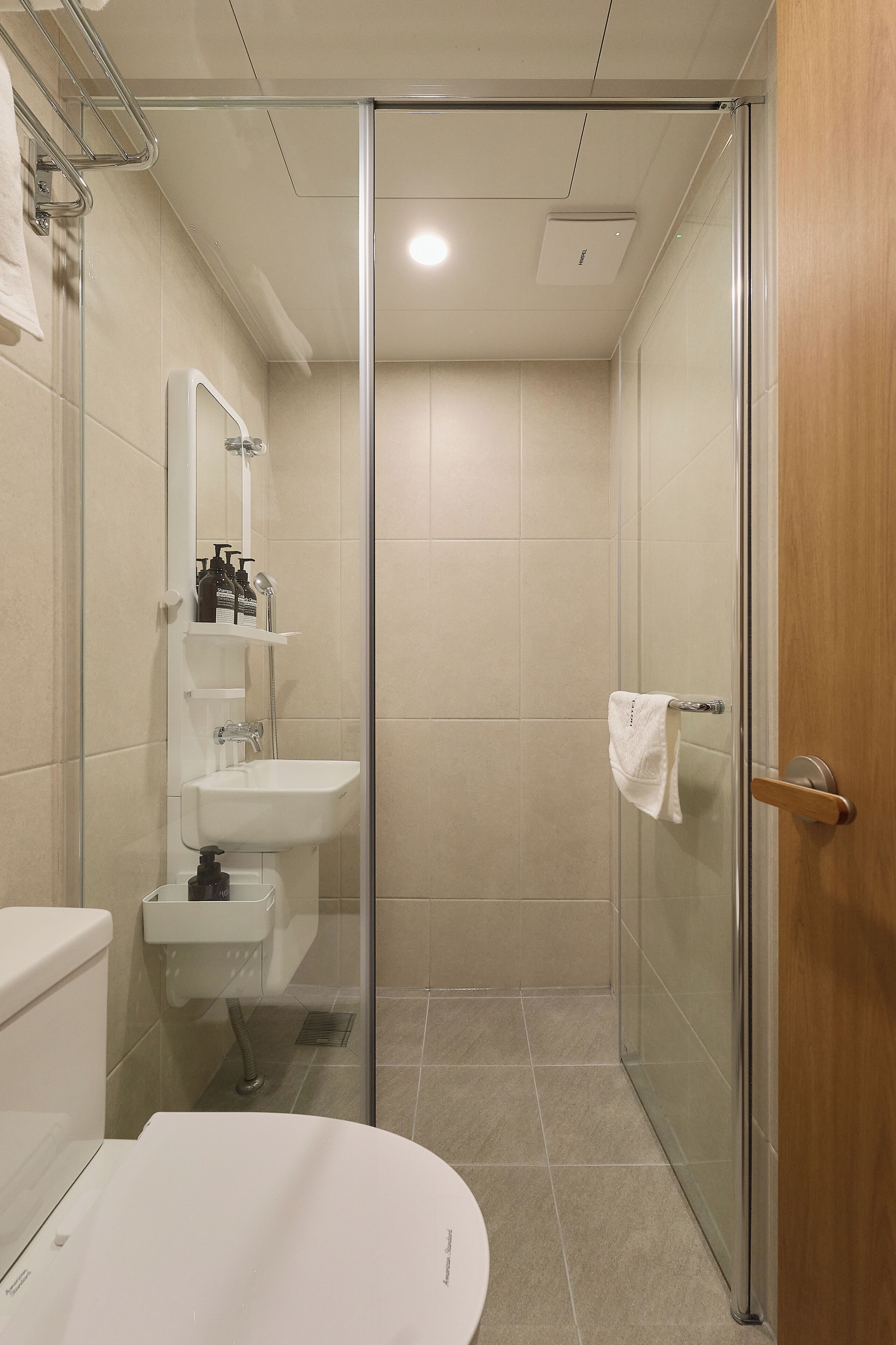 A modern bathroom with a glass shower enclosure, a white sink, and a toilet.