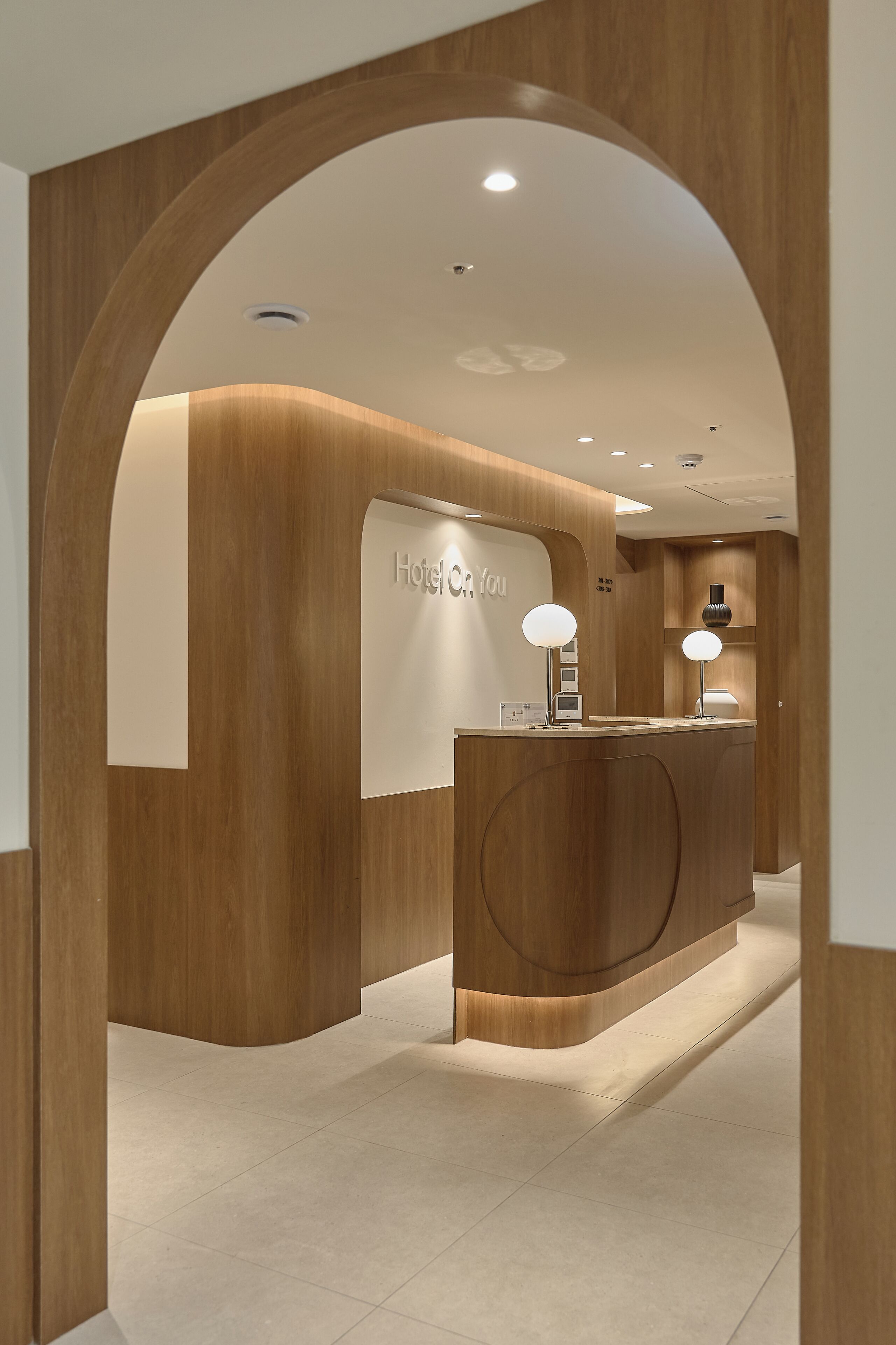 Ein Empfangsbereich mit Holzausstattung, einem Schild mit der Aufschrift 'Hotel On You' und einem modernen, minimalistischen Interieur.