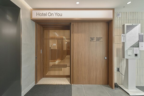 En hotelindgang med en trædør, et receptionsområde og et skilt, der angiver en lounge.