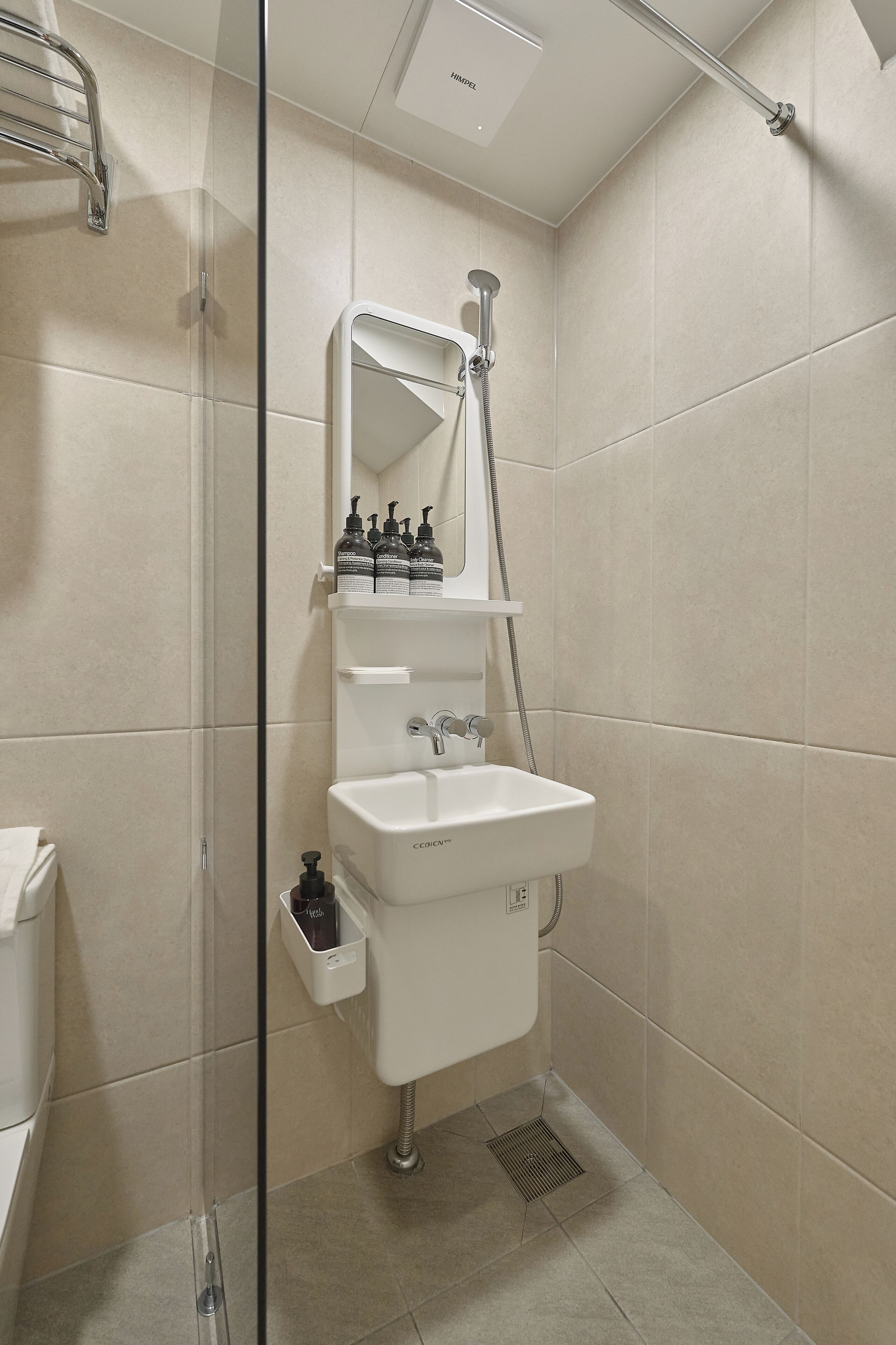 Un baño moderno con cabina de ducha de vidrio, un lavabo blanco y un espejo encima.