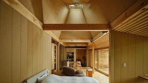 Ein Schlafzimmer mit einem Bett, einem Sofa und einem kleinen Tisch. Durch eine offene Tür ist eine Küchenzeile erkennbar.