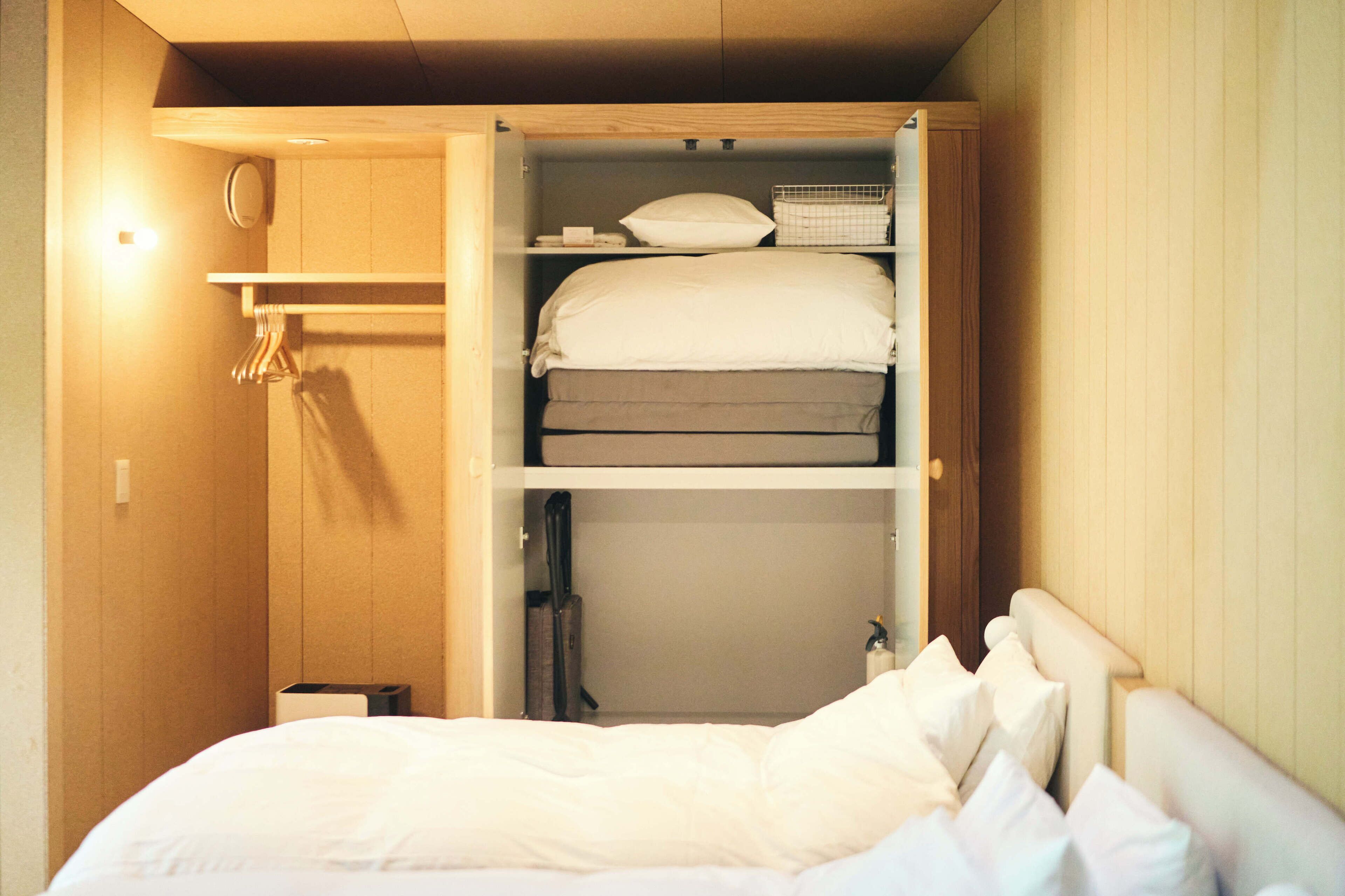 A compact bedroom with a bunk bed, a small bedside table, and a wardrobe with shelves.