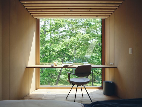 Ein modernes Schlafzimmer mit großem Fenster, einem Holztisch, einem Stuhl und einem Bett.
