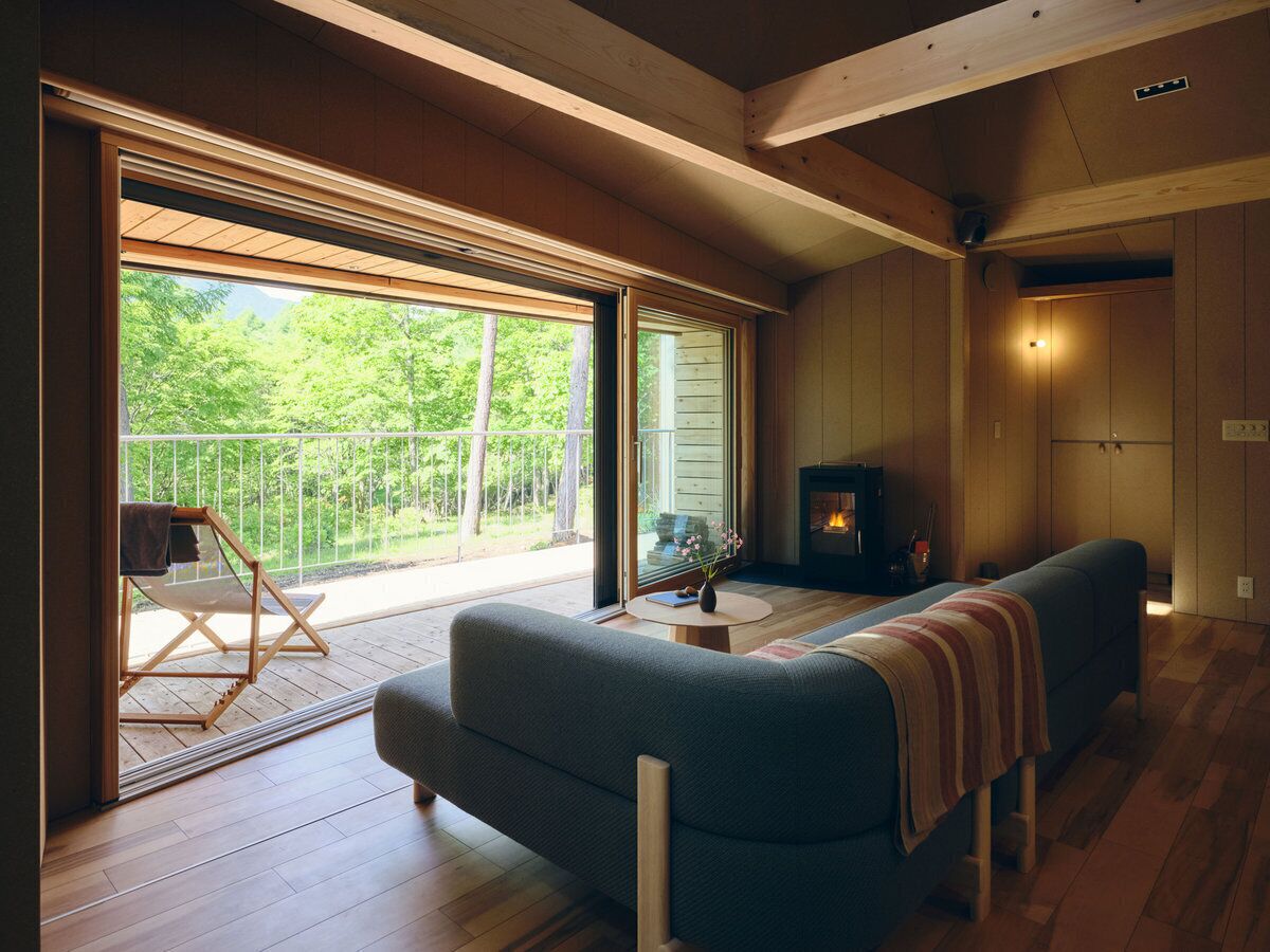 A cozy living room with a sofa, a small table, a fireplace, and a balcony with a chair.