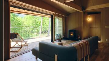 A cozy living room with a sofa, a small table, a fireplace, and a balcony with a chair.