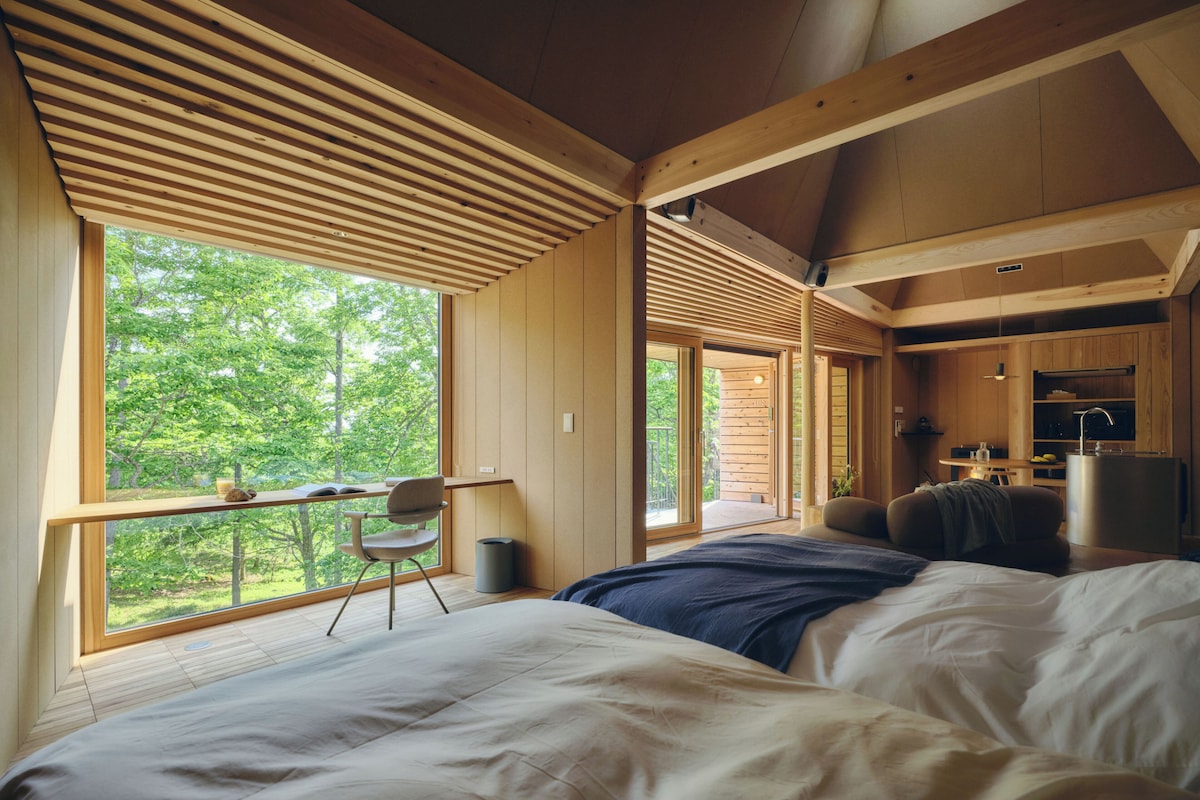 Een slaapkamer met een groot bed, een bureau en uitzicht op de omgeving.