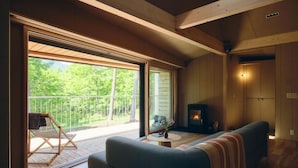 Ein gemütliches Wohnzimmer mit einer Couch, einem Kamin und einem Balkon mit einem Sessel.