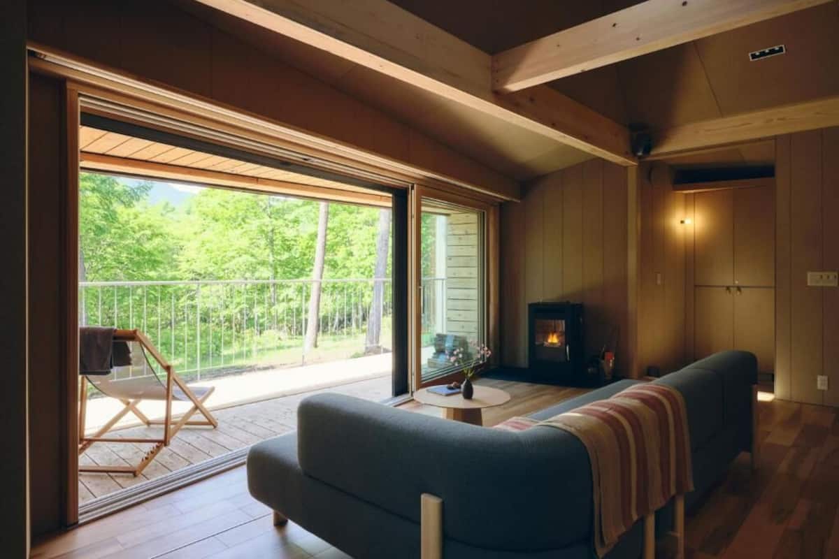 Un salon confortable avec un canapé, une cheminée et un balcon agrémenté d’une chaise.