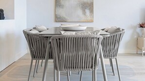 A modern dining area with a round table, grey upholstered chairs, and a minimalist abstract painting on the wall. - Riverside Luxe 2BR | Pool, Spa, Balcony and Parking (Vila Nova de Gaia)