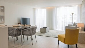 A modern living room with a dining area, large windows with sheer curtains, and a city view. - Riverside Luxe 2BR | Pool, Spa, Balcony and Parking (Vila Nova de Gaia)