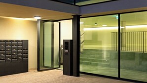 A modern building with a glass entrance, a mail slot, and a staircase leading inside. - Riverside Luxe 2BR | Pool, Spa, Balcony and Parking (Vila Nova de Gaia)