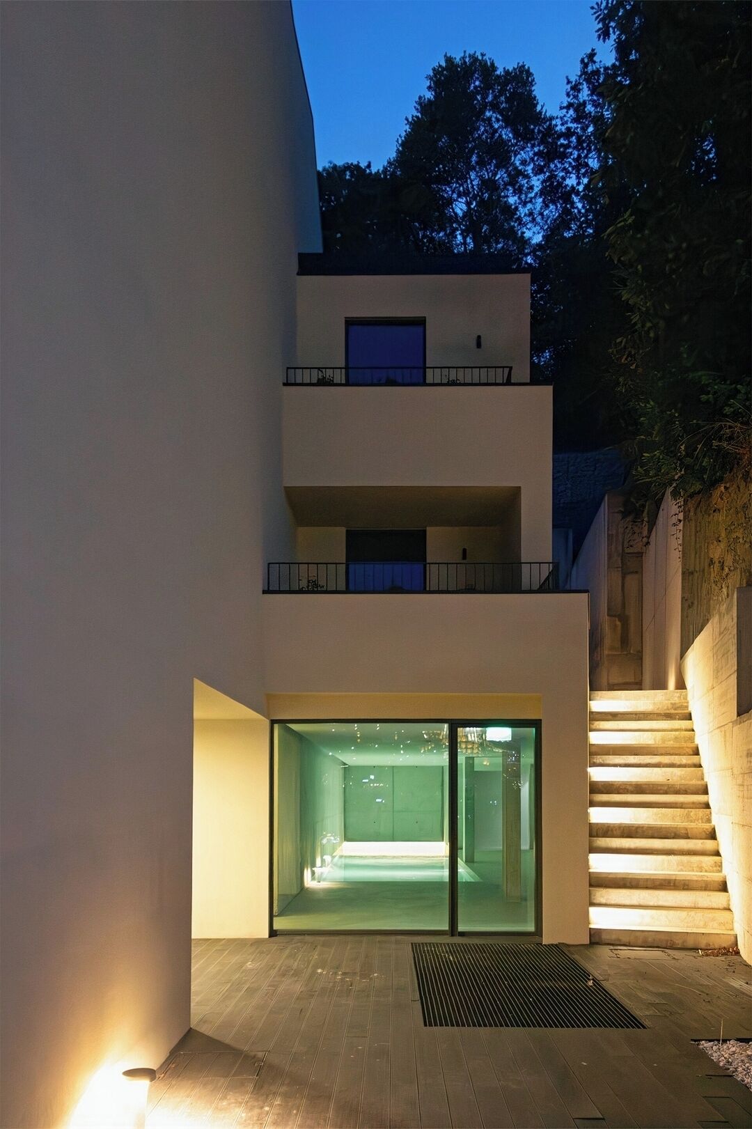 A modern building with a glass entrance, a staircase, and a balcony.