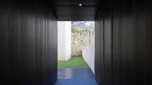 Um corredor de madeira escuro e estreito que leva a uma parede de pedra e uma área gramada.