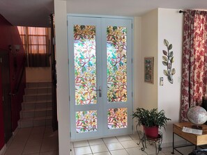 A room with a double door featuring stained glass, a staircase, a potted plant, a globe, and a wall-mounted decorative piece. - A Private Paradise by the Rainforest in Sunny Luquillo (Pitahaya)