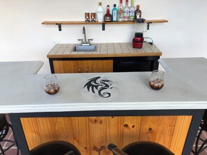 A bar area with a countertop, a sink, and a variety of liquor bottles. - A Private Paradise by the Rainforest in Sunny Luquillo (Pitahaya)